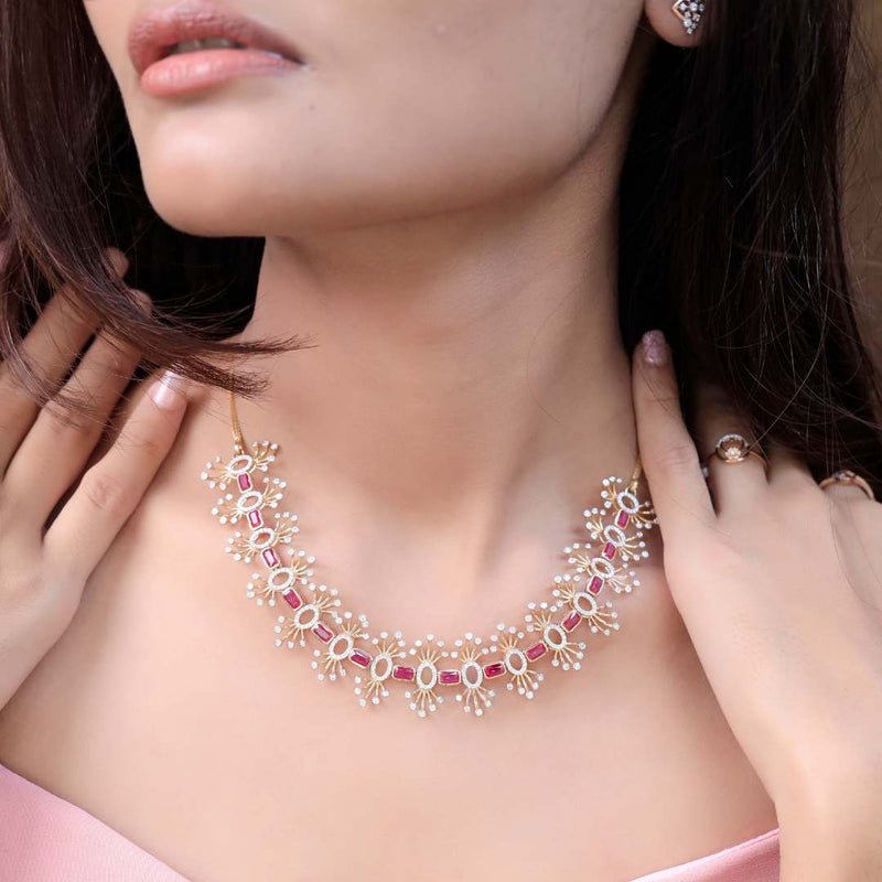 A close-up lifestyle shot of a model wearing a delicate gold necklace adorned with small white pearls and pink gemstone accents, paired with matching pearl and gold earrings.